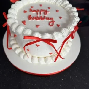 Gâteau d'anniversaire vintage blanc, inscription happy birthday et nœuds rouges