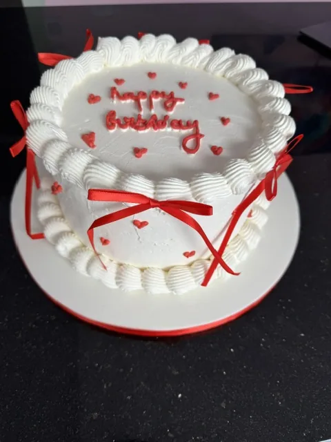 Gâteau d'anniversaire vintage blanc, inscription happy birthday et nœuds rouges