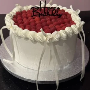 Layer cake blanc garni de framboises, nœuds ivoire et topper Happy Birthday
